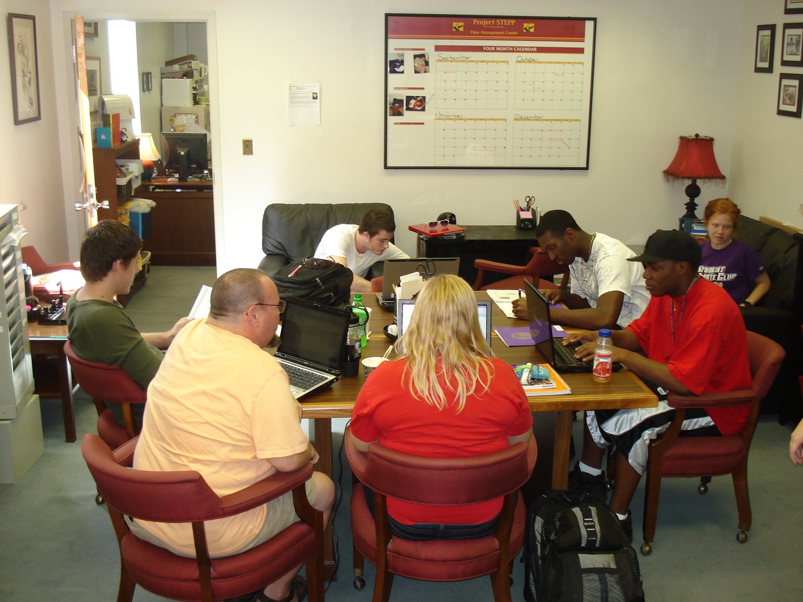 tutor and students sitting around a table working in the old STEPP office