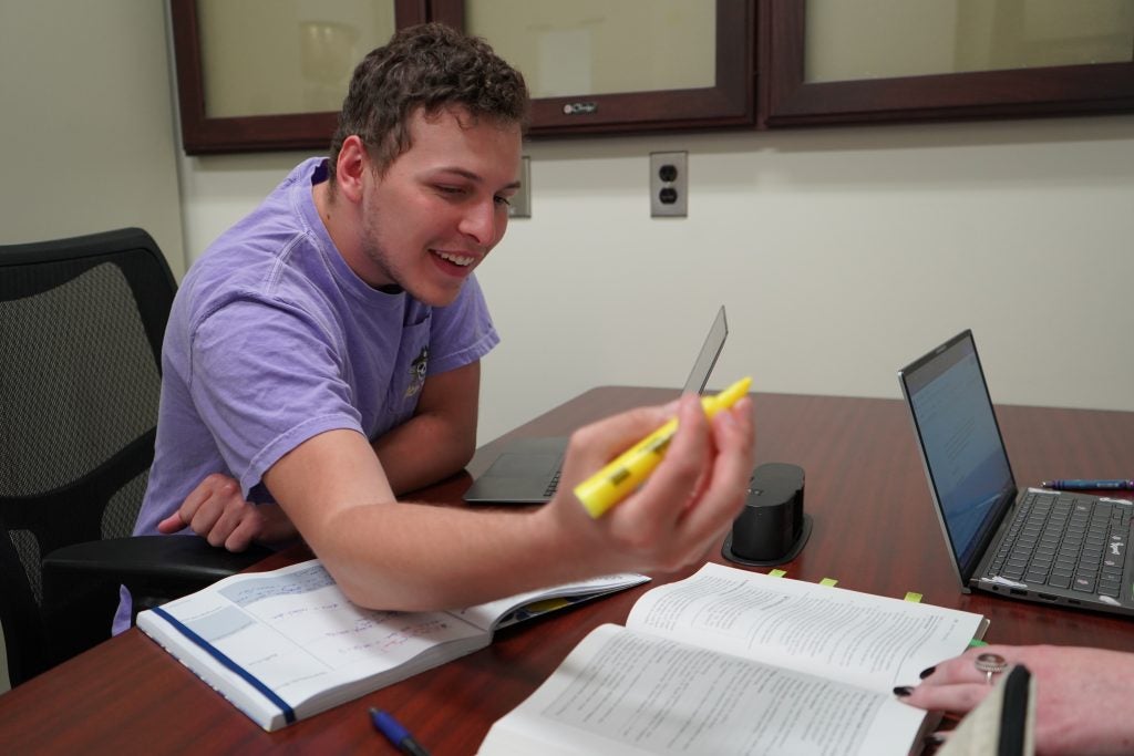 student sitting at desk using a highlighter during a mentor meeting